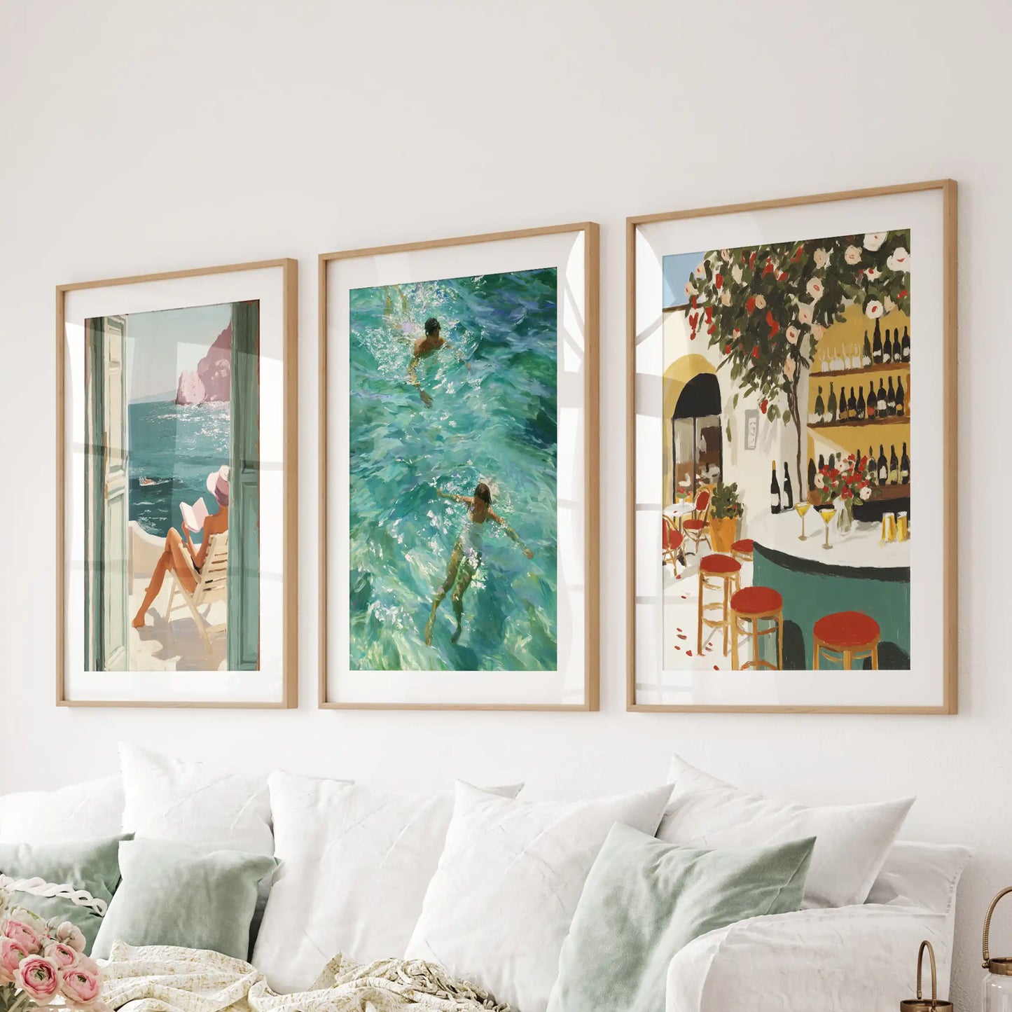 Mediterranean beach landscapes, three-piece wall art in natural wood matted frames, arranged behind the living-room sofa for a relaxed coastal line.