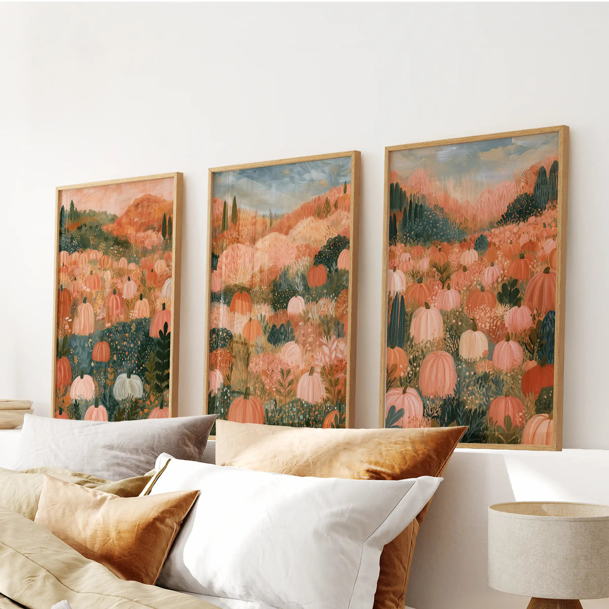 A set of three wall hangings features folk art pumpkins in solid oak frames, centered over the bedroom bed with nostalgic autumn tones.