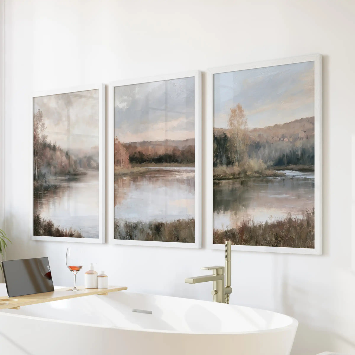 A three-piece art set of autumn woodland by the water hangs in crisp white frames over the bathroom tub, bringing calm, gentle neutral tones.