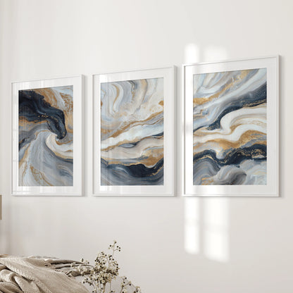 Blue and beige fluid swirls with gold, a gallery of three art prints, are white framed with mats and styled on the bedroom wall beside the bed.