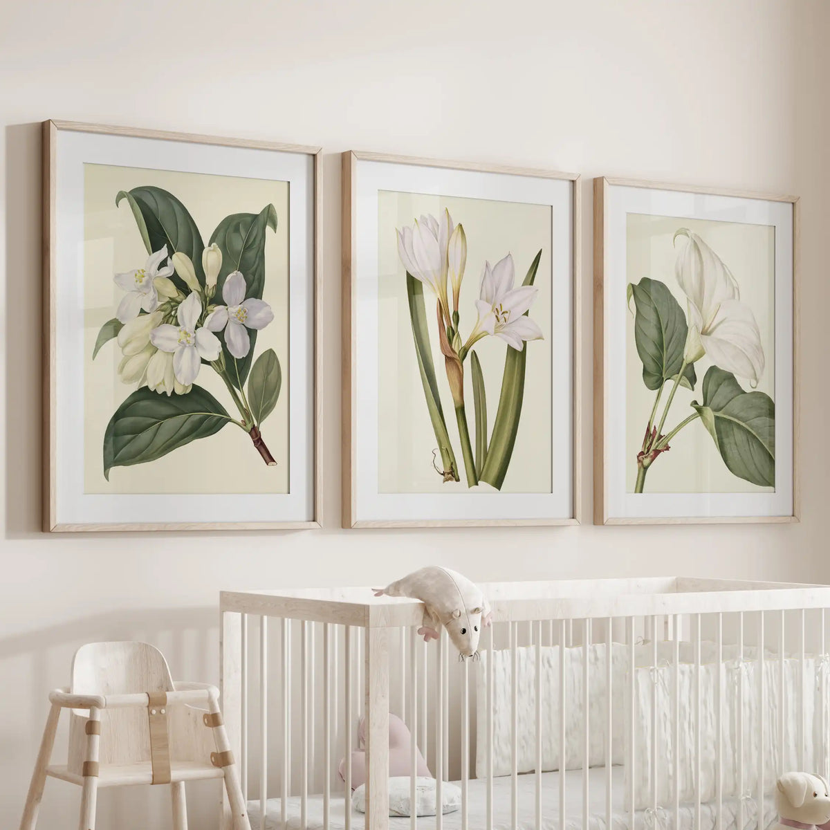 A set of three white flowering stem prints above a crib, in oak frames with white mats.