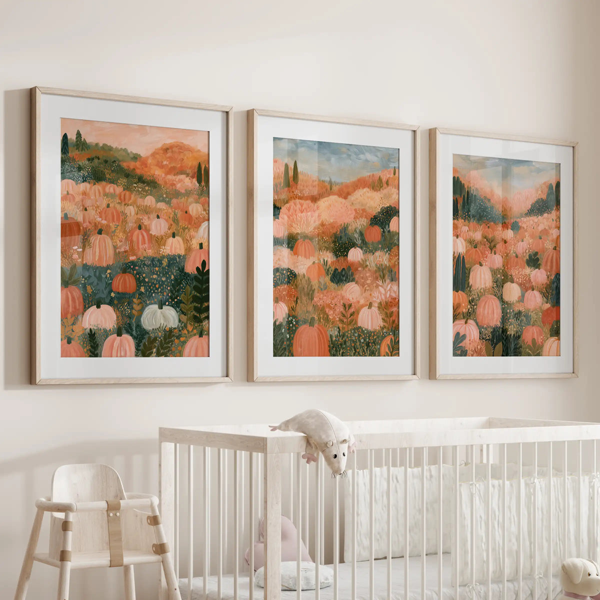 Three wall art prints of a pastel pumpkin field sit in matted light oak frames above the infant-room cot, creating a soothing fall touch.