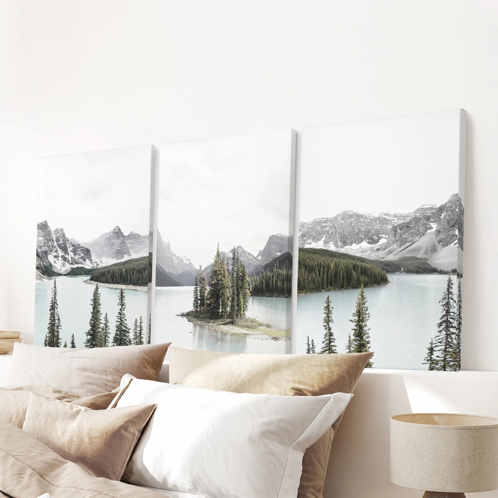 A gallery set of three canvas prints of the Canadian Rockies rises above the headboard, framing the bedroom with misty ridgelines and soft light.