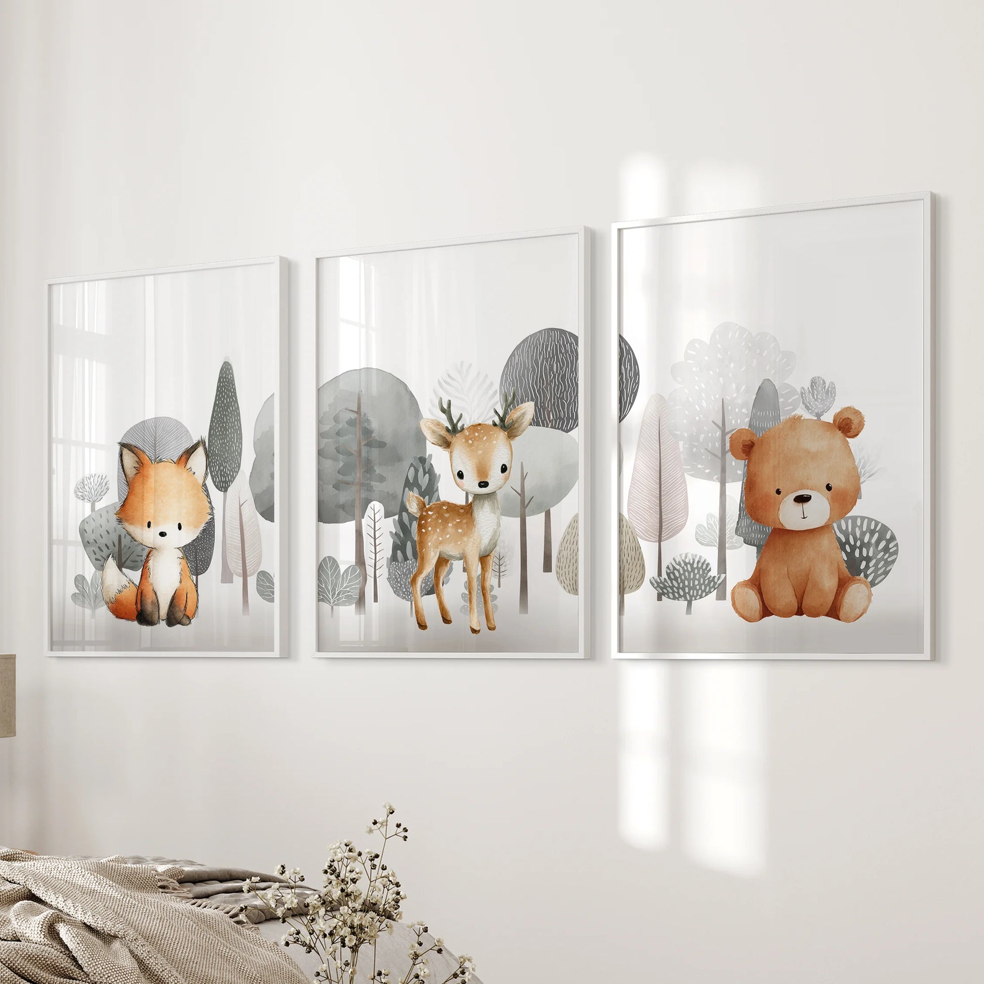 Cuddly woodland creatures in a three-piece picture set, shown in clean white frames, brighten a bedroom wall next to the bed.