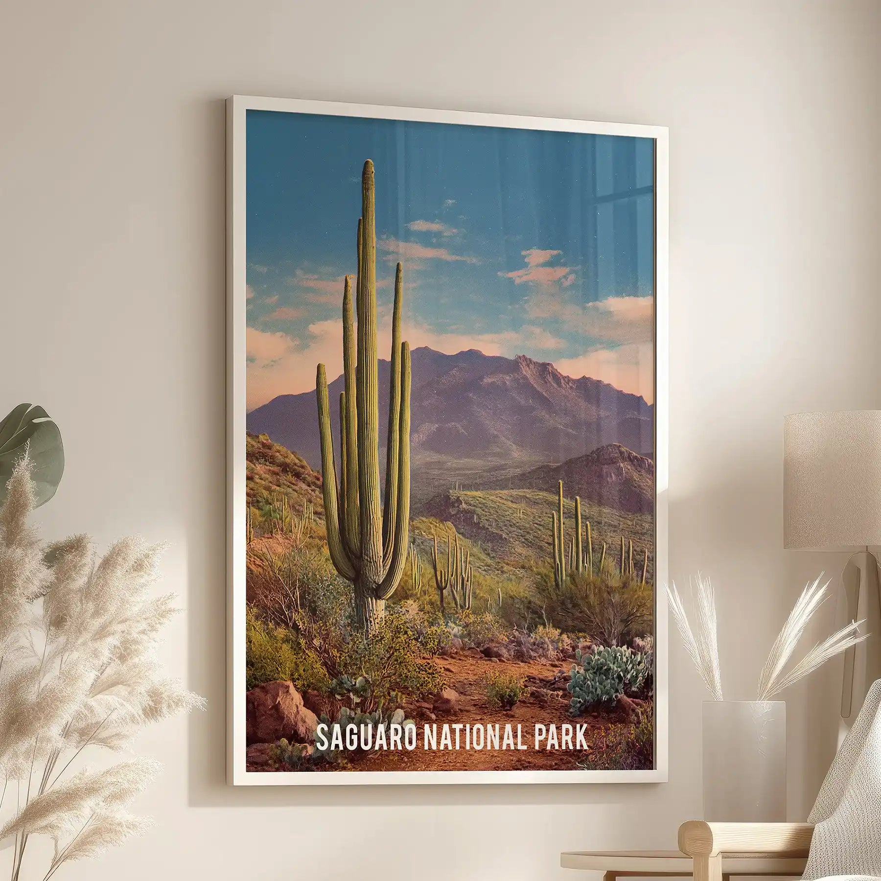 White-framed desert scenery wall art leans near the lounge reading chair, adding a soft, airy focal point against the relaxed setting.