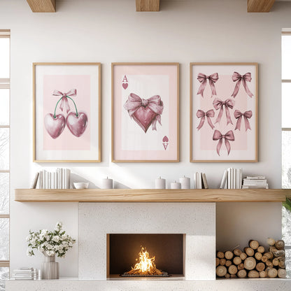 Light-wood frames hold a pink-bow trio above the mantel, a three-piece artwork gently lifting the sitting room with a blush, airy feel.