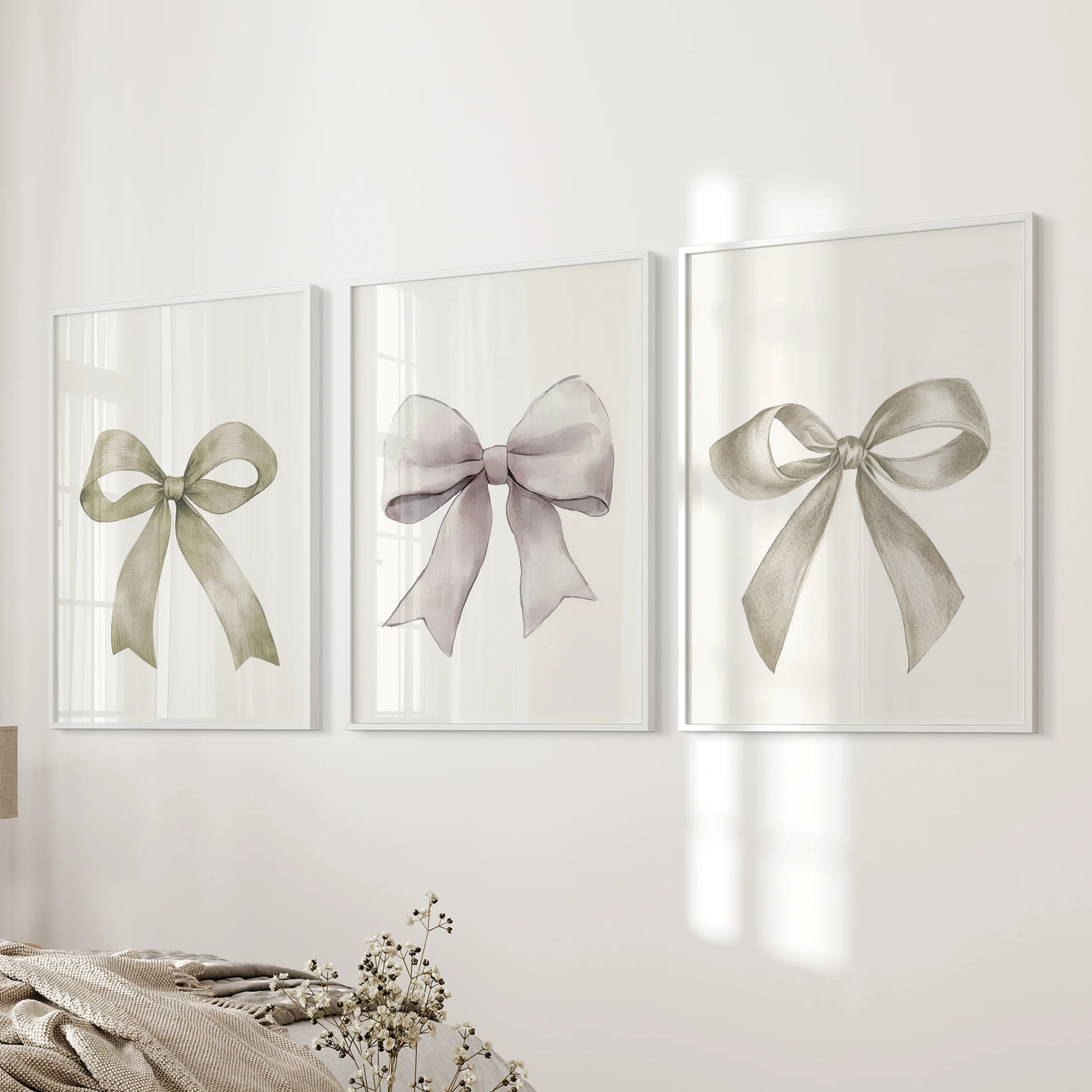 A trio of minimalist ribbon prints in clean white frames lines the bedroom wall by the bed, softening the room with gentle bow outlines.