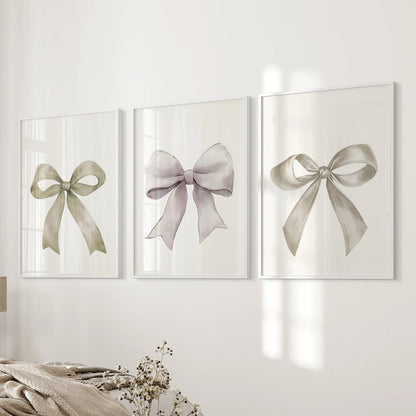 A trio of minimalist ribbon prints in clean white frames lines the bedroom wall by the bed, softening the room with gentle bow outlines.