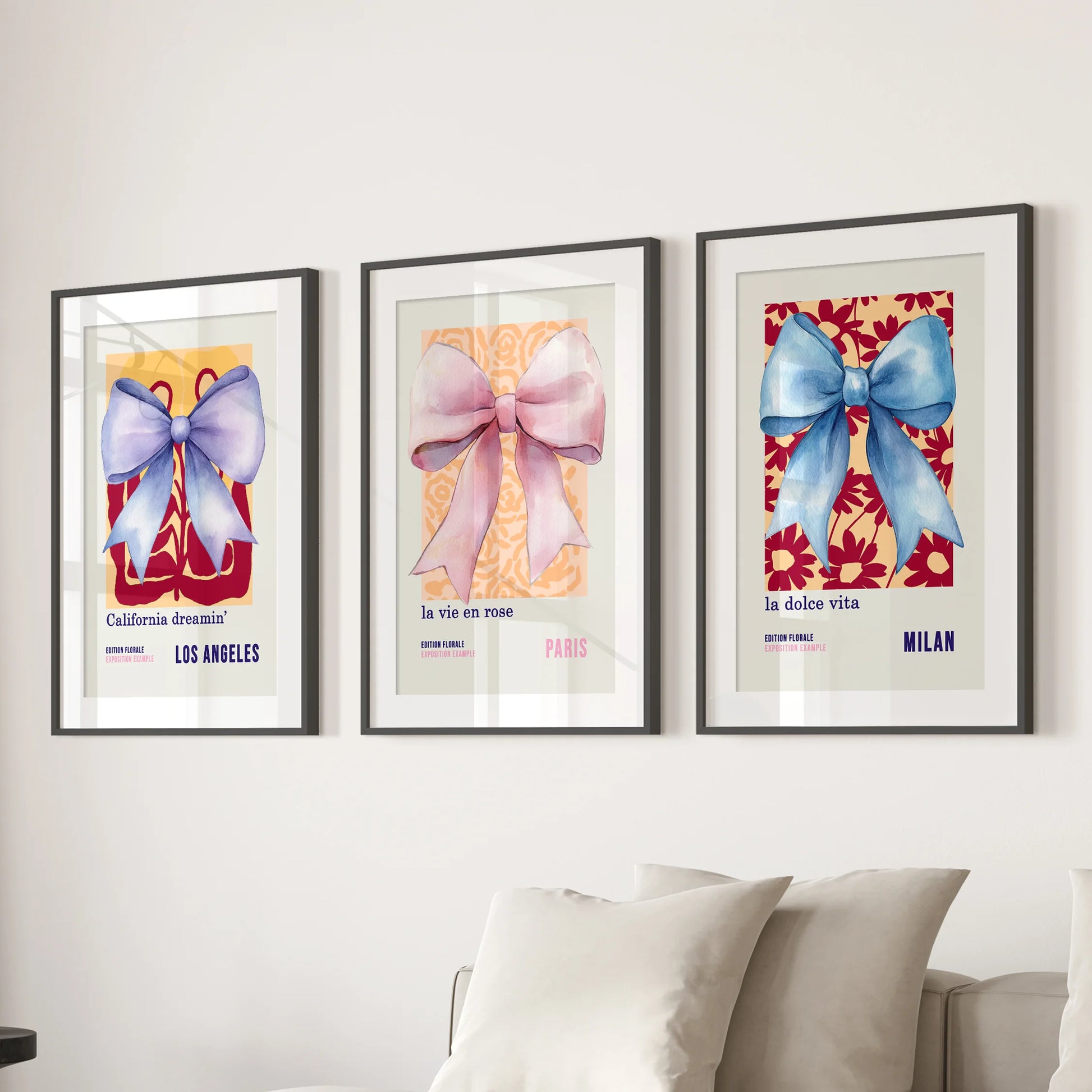 Preppy coquette bows, three-piece art prints with black mats and frames, anchor the lounge above the couch with soft blue-and-pink watercolor flair.