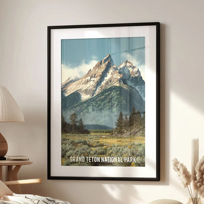 This wall artwork of an alpine valley and pine forest, framed in black with matting, rests beside a reading chair to evoke calm Wyoming wilderness.