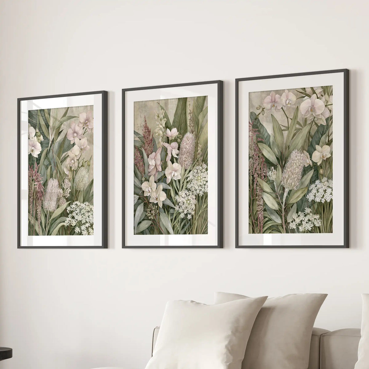 Matted black frames hold three tropical botanical prints above a sofa.