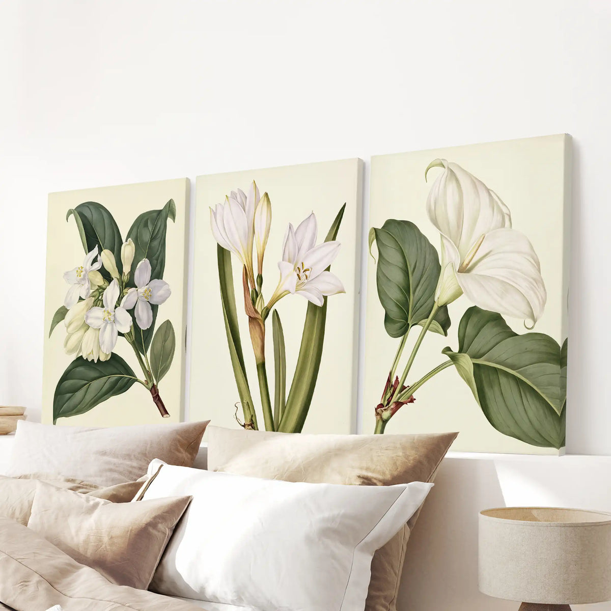 Small flower clusters, upright stems and a broad-leafed white bloom fill three cream-backed canvases above the bed pillows.