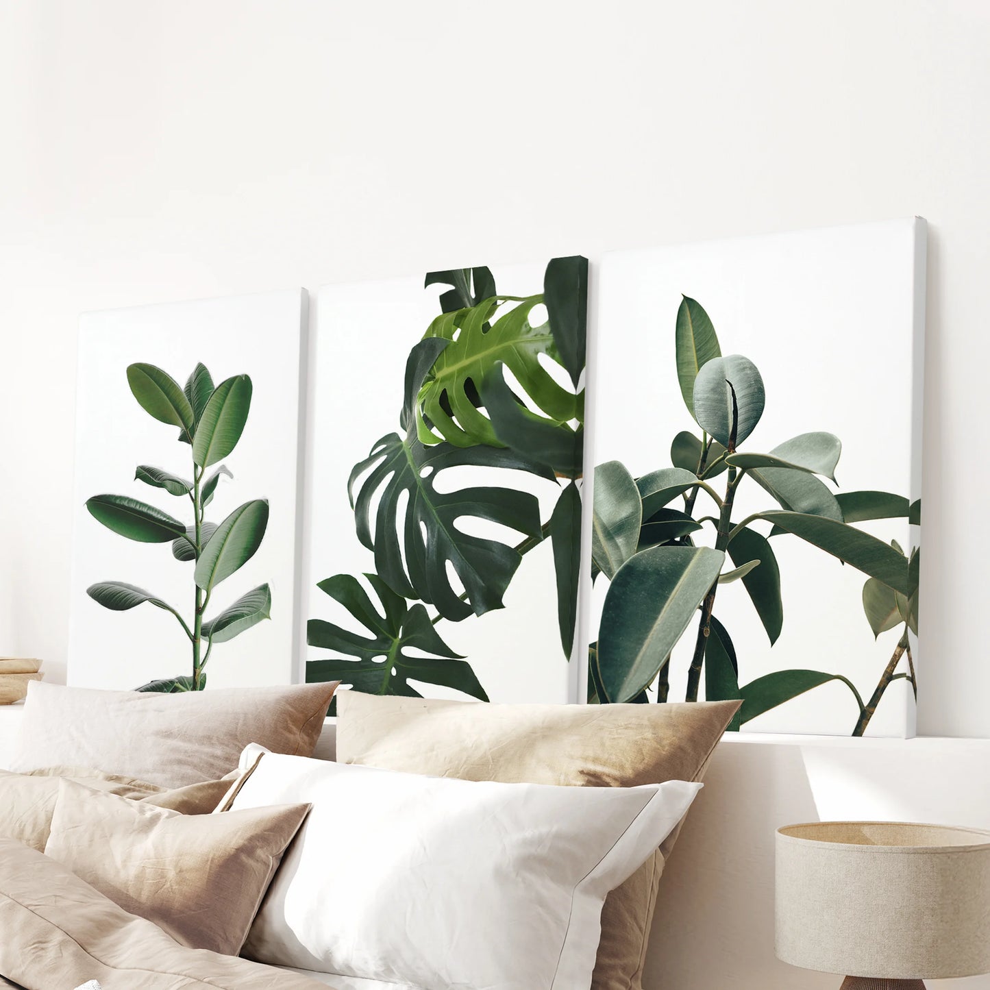 A three-panel gallery-wrapped set of green leaves crowns the bedroom wall above the headboard with lush botanical energy.