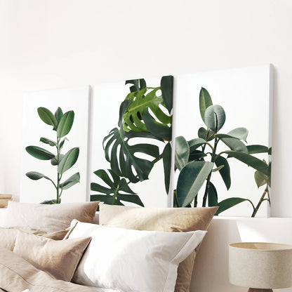 A three-panel gallery-wrapped set of green leaves crowns the bedroom wall above the headboard with lush botanical energy.