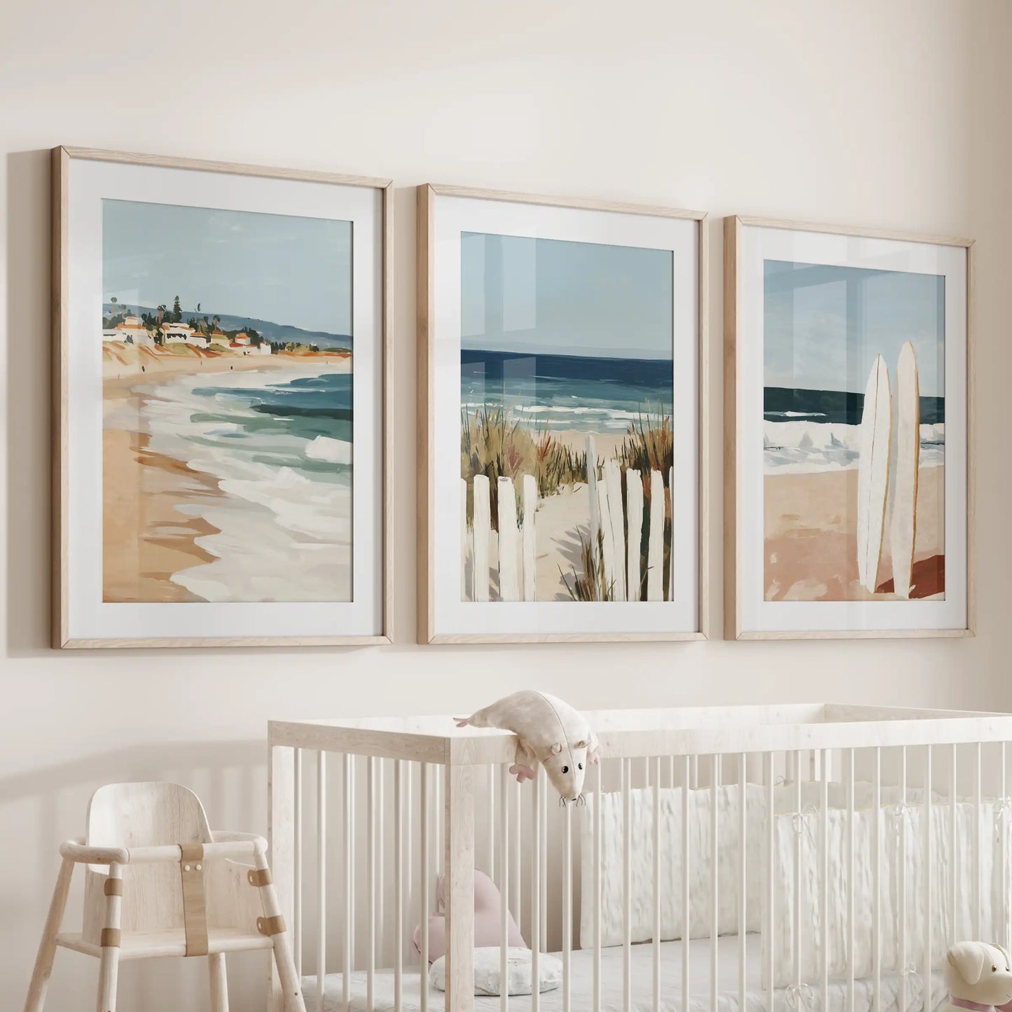 Three oak-framed ocean landscape prints with soft mats hang above the nursery cot, surrounding the space with a gentle sea-breeze tone.