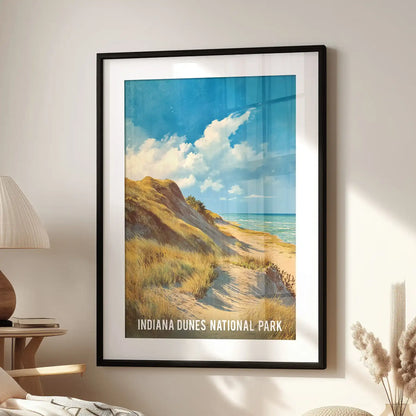 Vintage-style beach travel poster print of the Indiana Dunes, in a black frame with matting, presented in a living room over an armchair.
