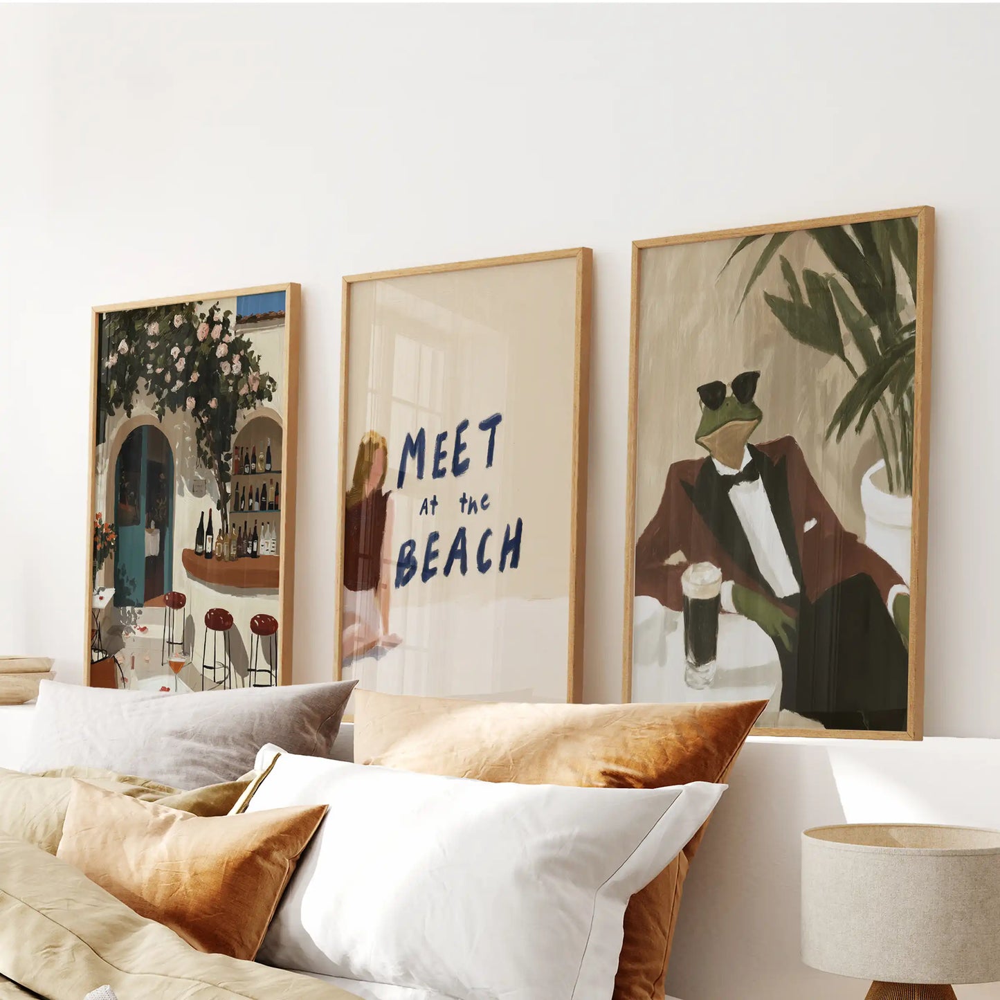 A sun-washed three-piece Mediterranean beach hanging in warm wooden frames brings an easy, relaxed feel above the bed.