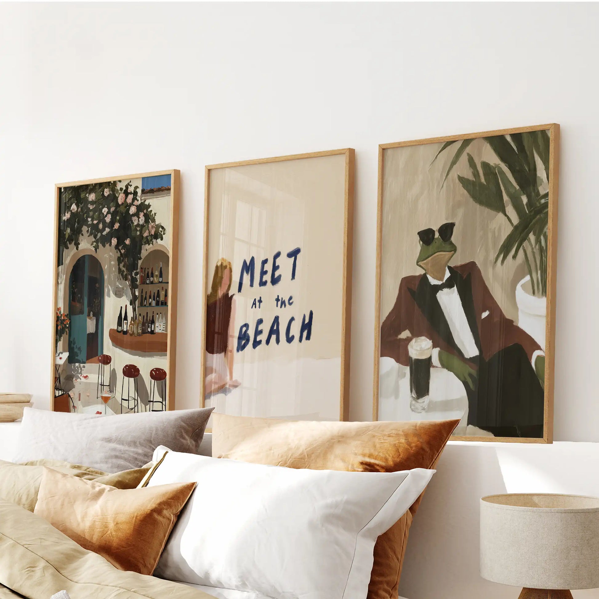 A sun-washed three-piece Mediterranean beach hanging in warm wooden frames brings an easy, relaxed feel above the bed.