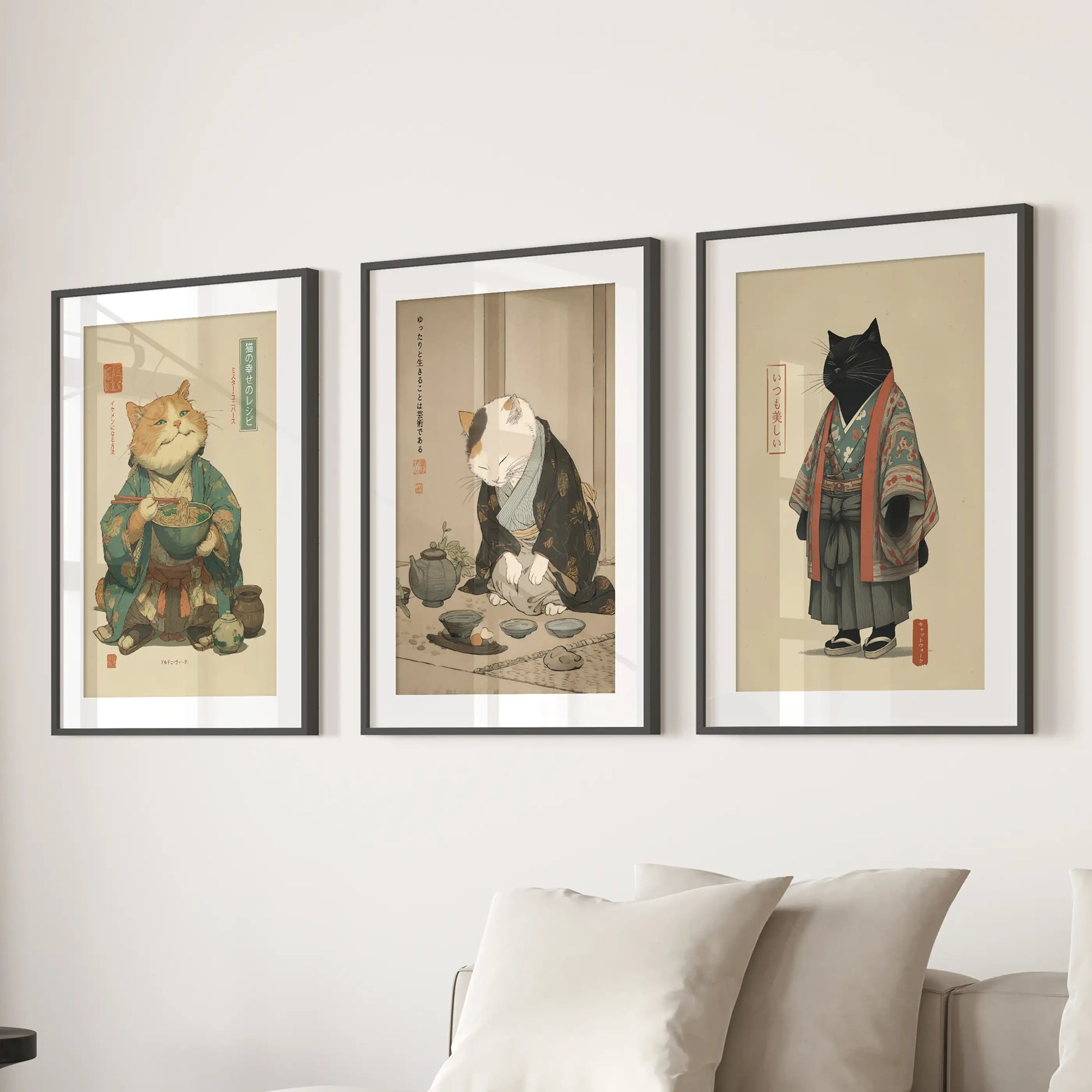 A set of three cat art prints in black frames with matting stretches above the lounge sectional, crisp and graphic with ramen-bowl humor.