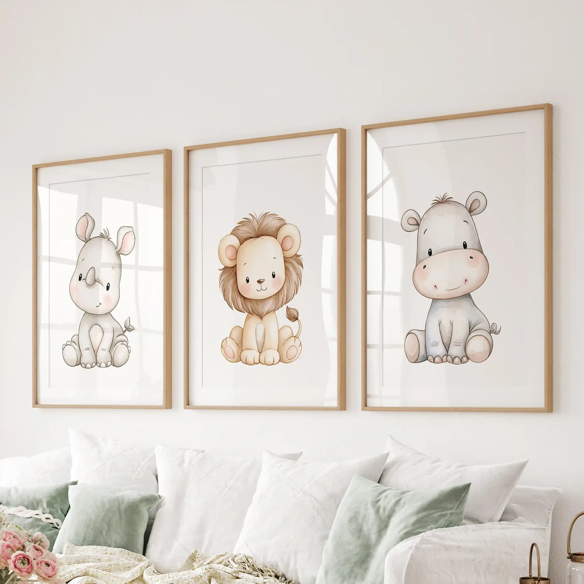 Safari animal prints in three oak frames with white mats hang above a sofa.