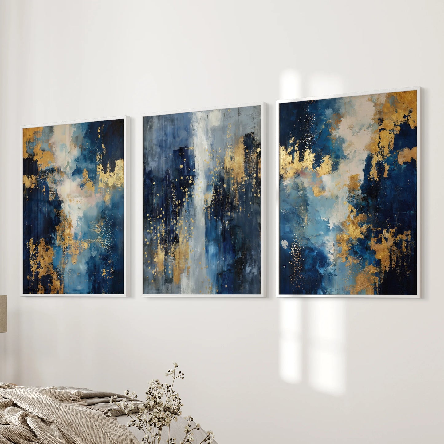 Blue and gold oil paint textures in a 3-piece picture set with slim white frames hang near the bedroom bed wall, creating crisp, upscale wall decor.