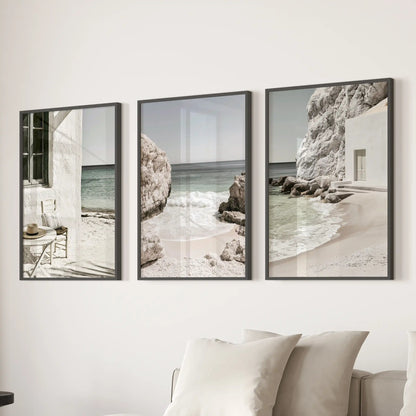 A 3-wall-art set presents Mediterranean coastline vistas in slim black frames, placed over the sofa to fill the sitting room with serene neutral tones.