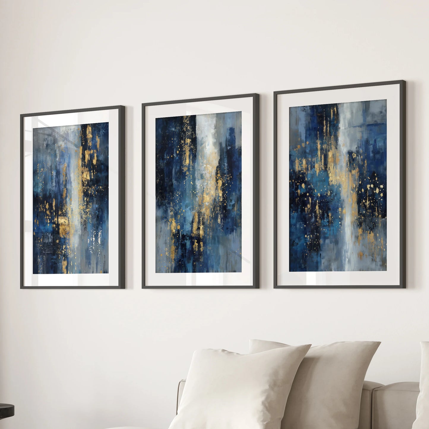 Three framed art prints featuring gold sparkle on deep navy hang above a sectional sofa, adding polished warmth to the lounge.
