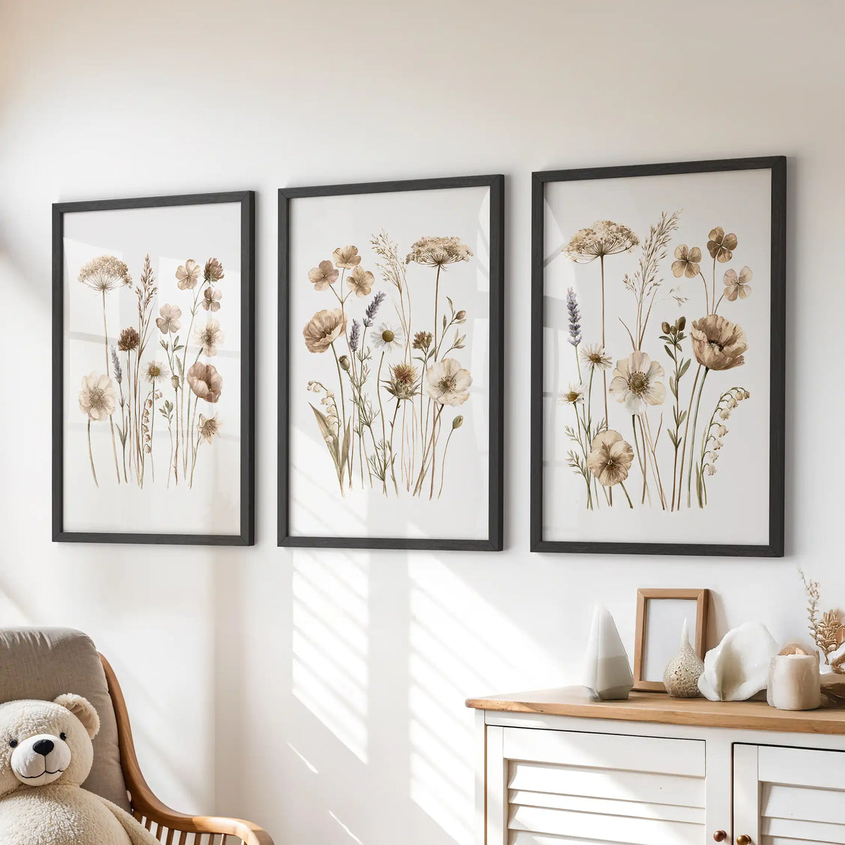 Fine meadow stems with beige and brown flower heads fill three black-framed prints above a dresser, with taller umbrella-shaped blooms near the top.