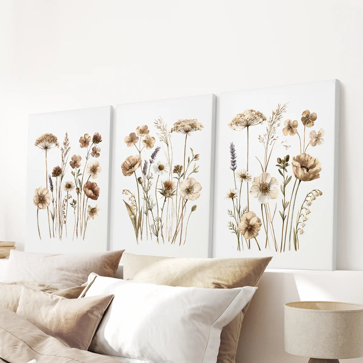 Fine meadow stems with beige and brown blooms stand on white backgrounds across three canvases above a bed, with a purple sprig at right.
