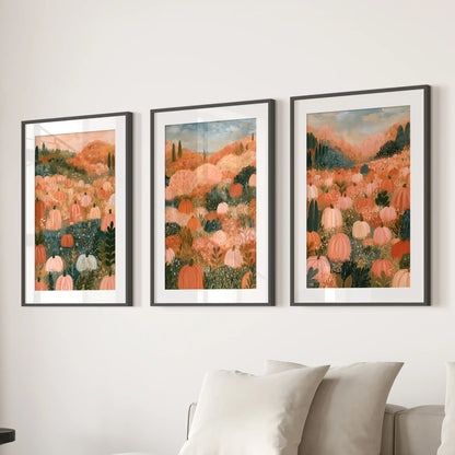 Three wall prints feature an autumn meadow landscape in black frames with white mats, arranged calmly above the family-room sofa.