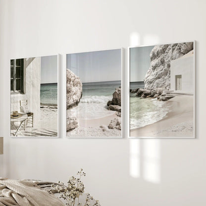A three-piece art set showcases Mediterranean coastline vistas in crisp white frames, centered on a bedside wall for a quietly coastal bedroom mood.