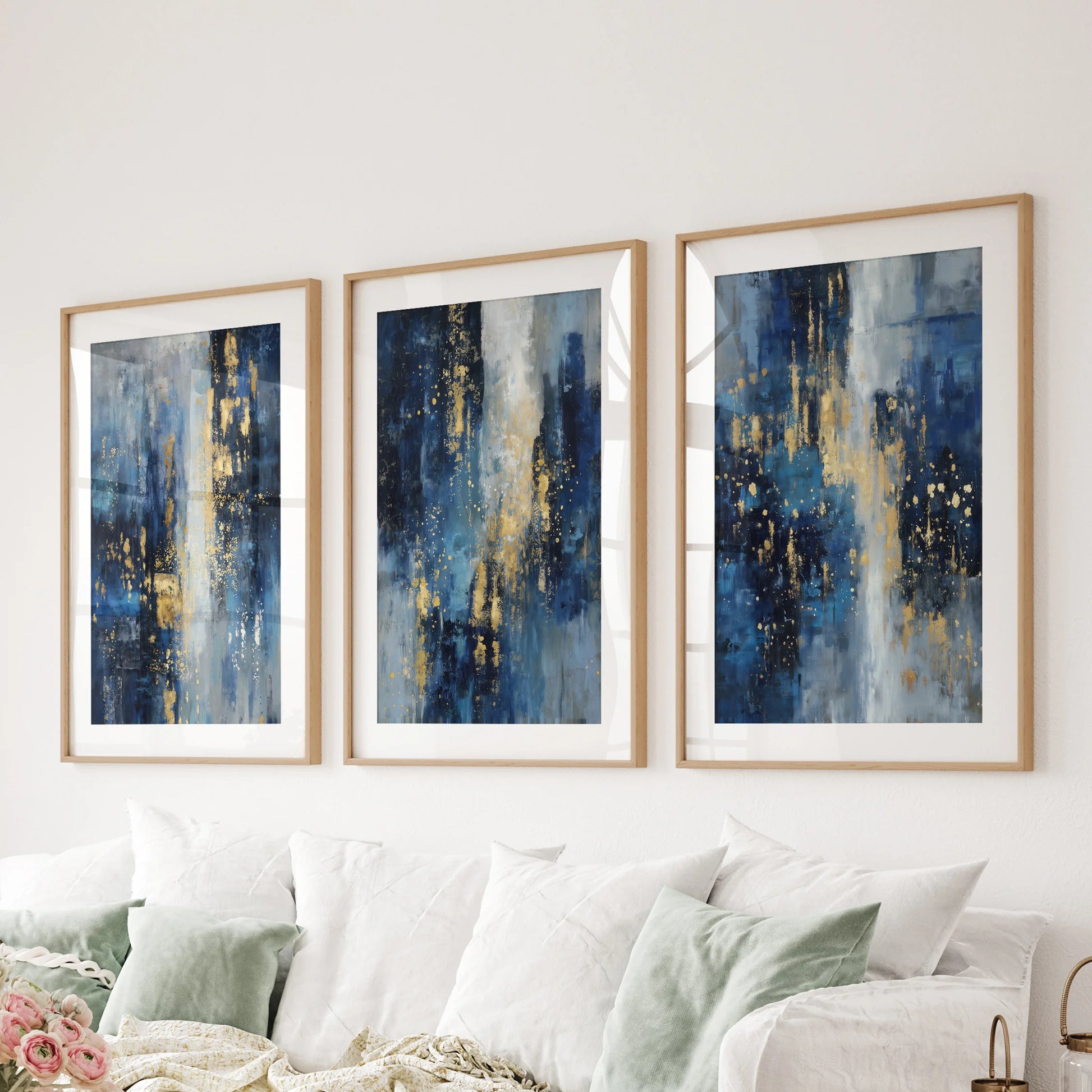 A three-panel blue and gold abstract set in natural wood-matted frames anchors the lounge wall above the sofa with modern balance.
