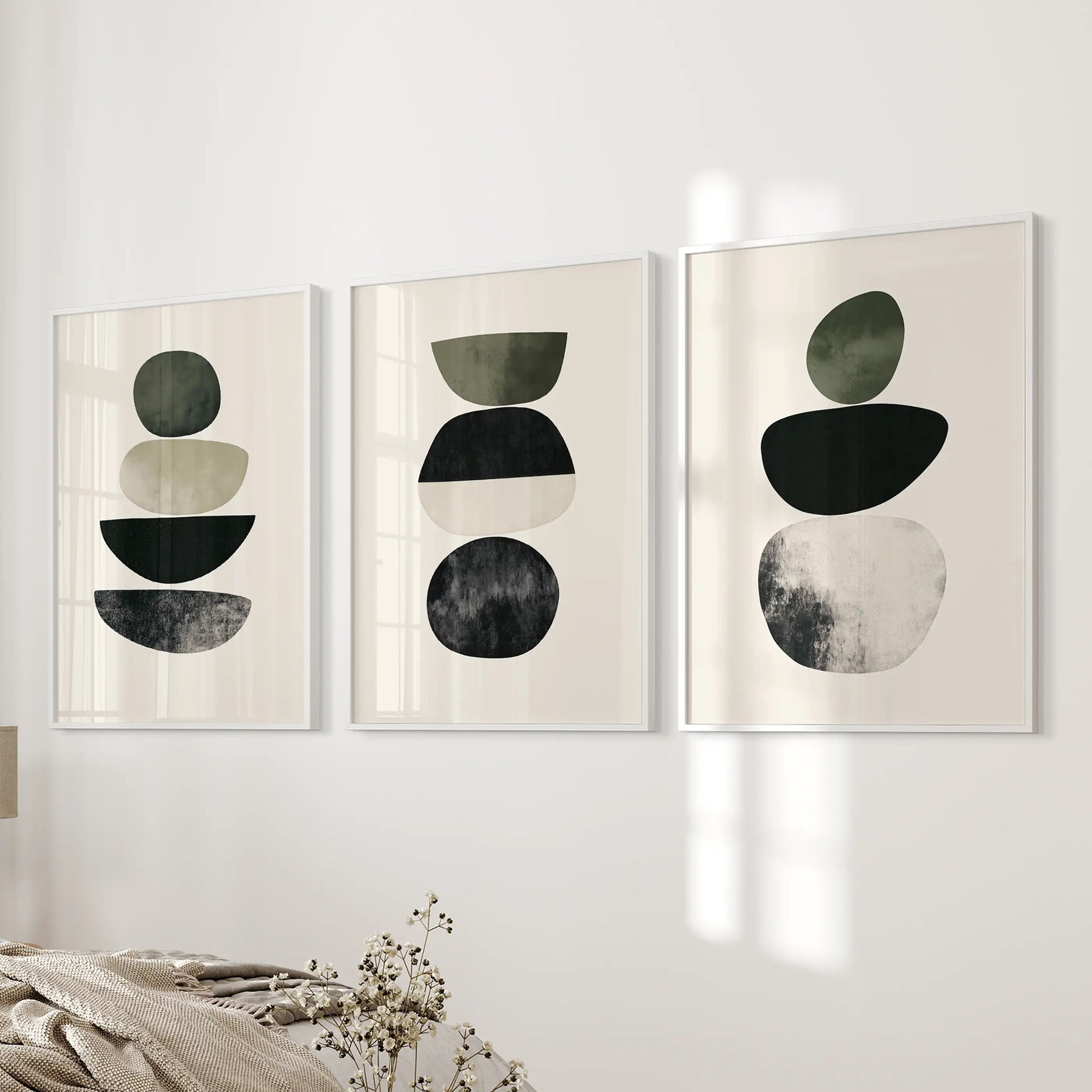 Organic shapes in a neutral palette three-print set offers quiet wall art for the bedroom, finished with white frames on the wall beside the bed.