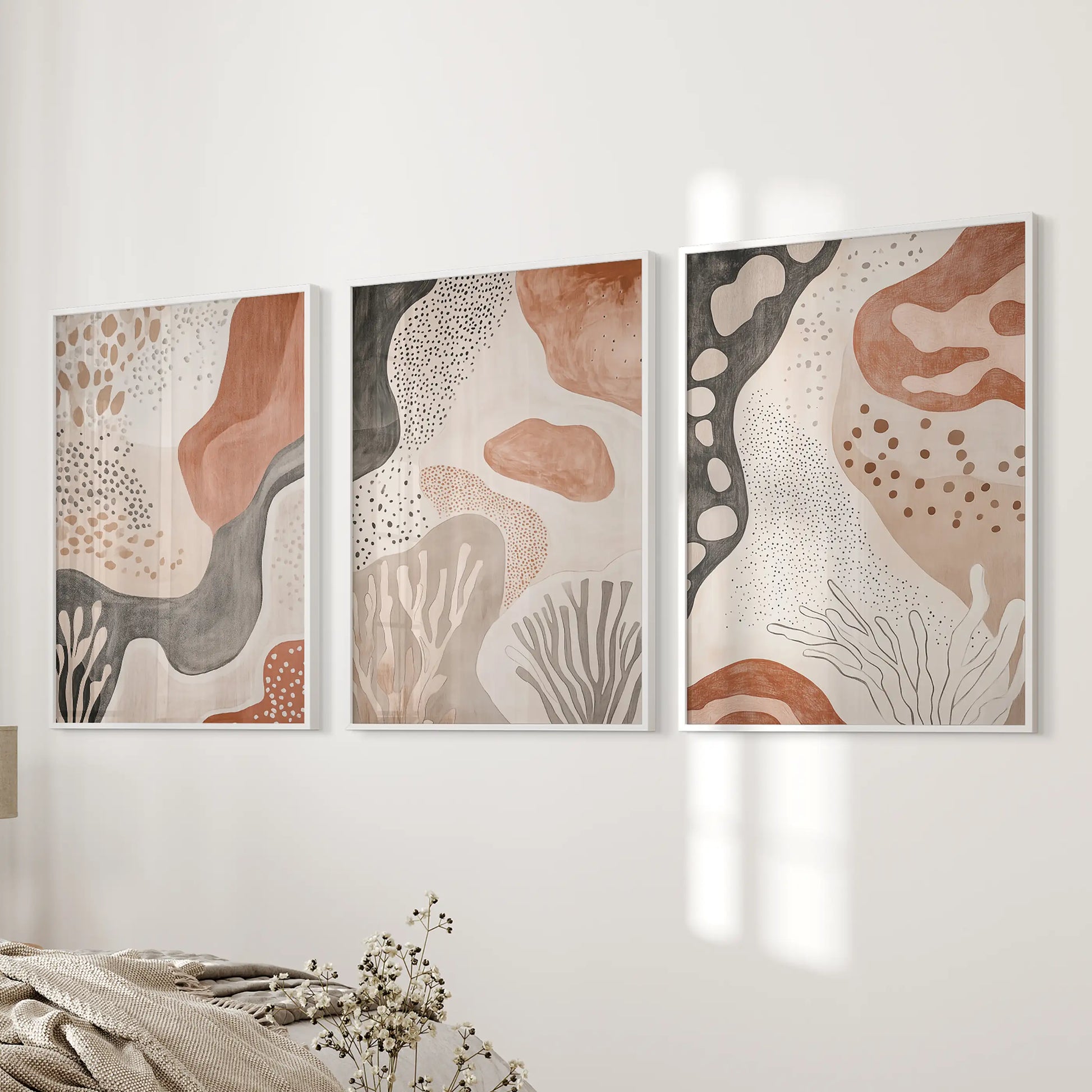 Three white-framed boho prints rest beside the bed, echoing a mid-century spirit with clean, balanced shapes.