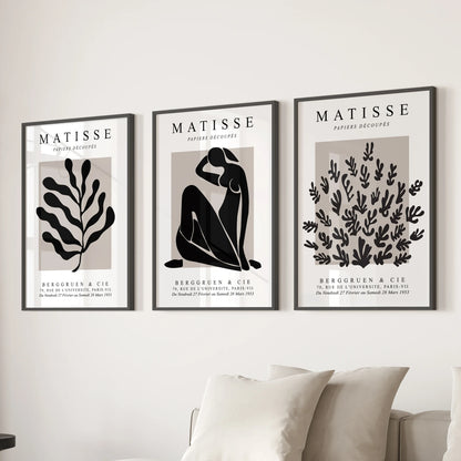 A living room wall display of three black-framed posters with beige and black abstracts adds a grounded touch above the couch.