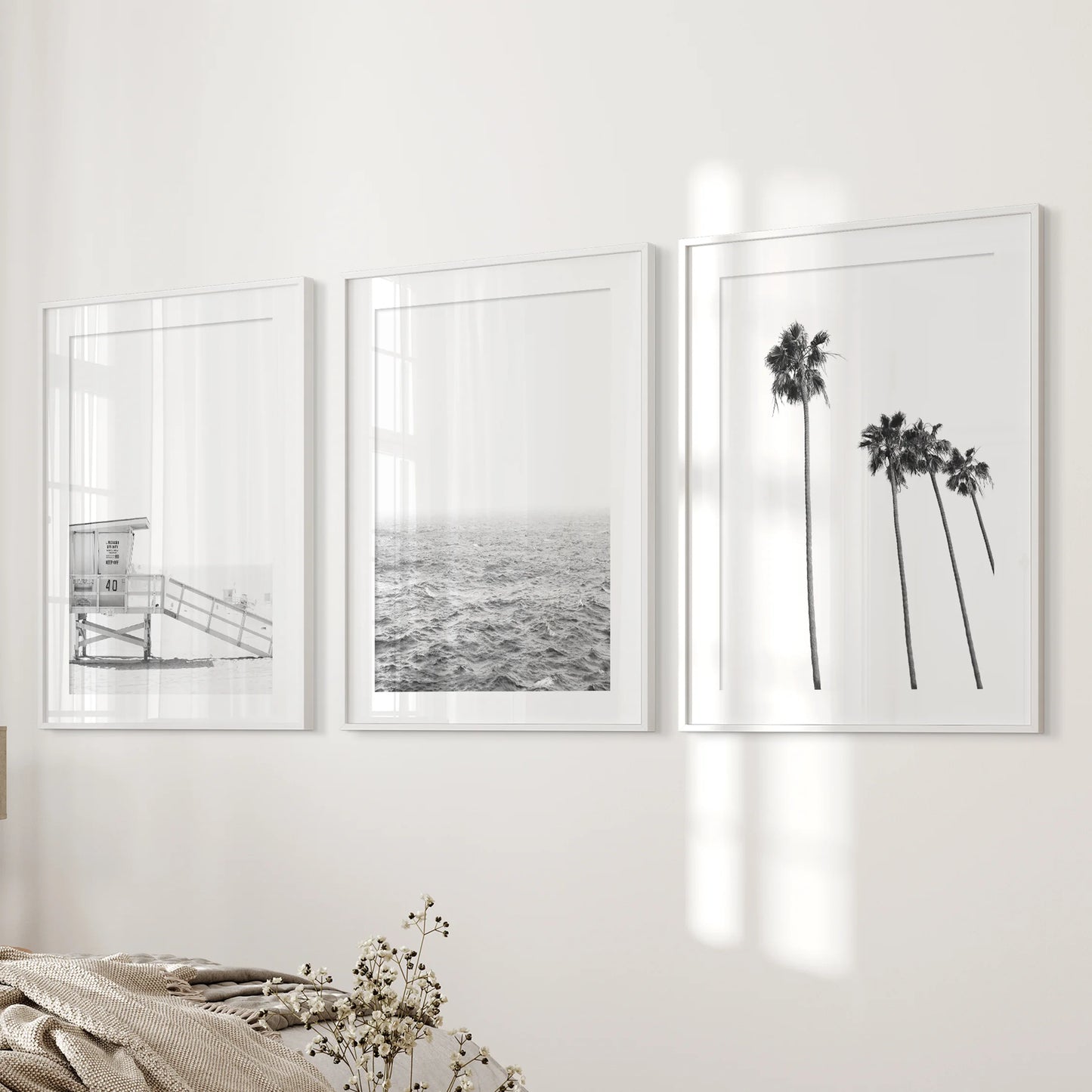 Beach cabin, a set of 3 prints in white frames with matting, steadies the bedroom's bedside wall with calm, sun-bleached coastal texture.