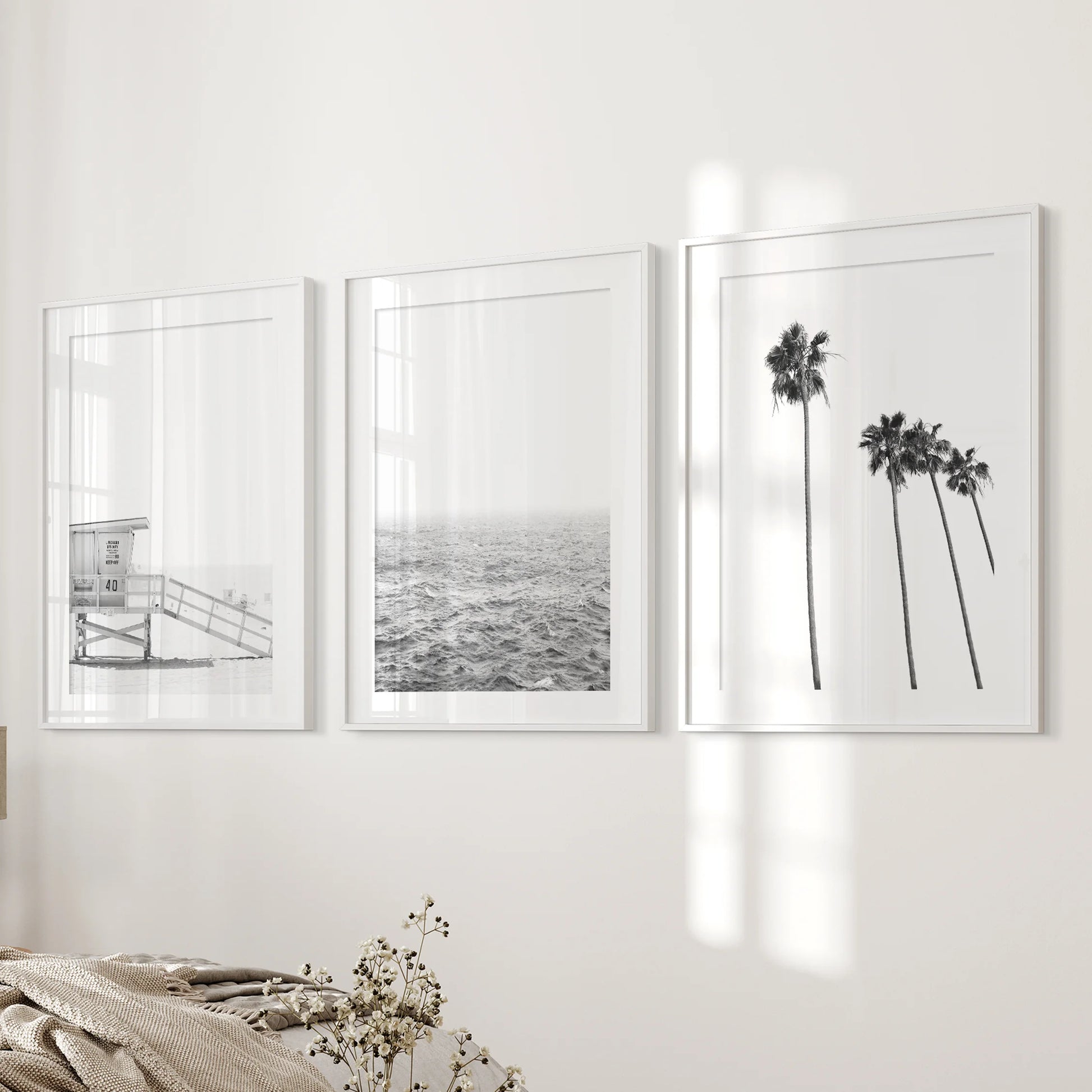 Beach cabin, a set of 3 prints in white frames with matting, steadies the bedroom's bedside wall with calm, sun-bleached coastal texture.
