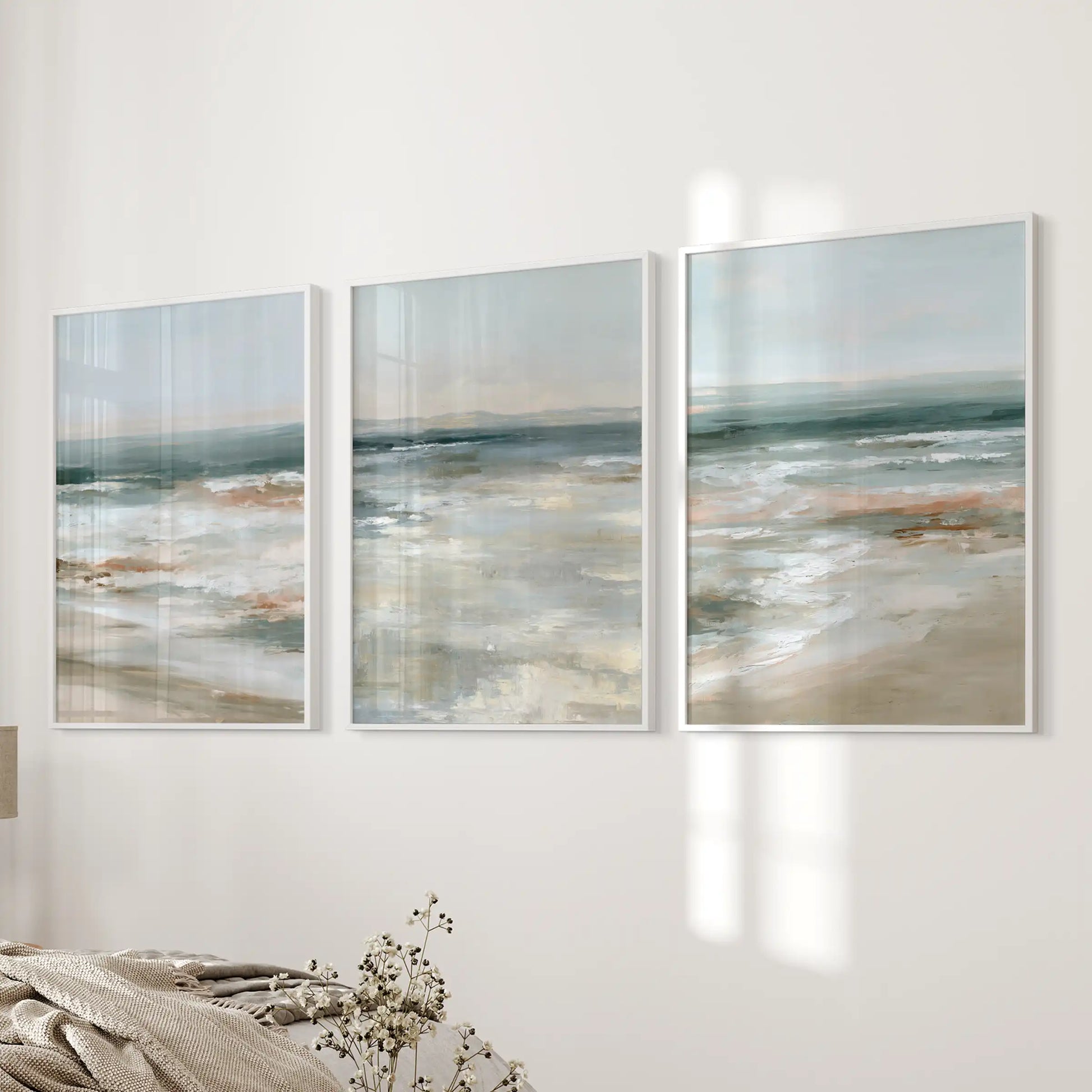 White-framed beach scene prints, a set of three, frame the wall beside the bed and keep the bedroom’s palette gentle and minimal.