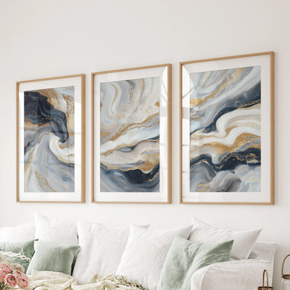 Three minimalist blue and gold art prints, matted in wood frames, stretch across the living room wall behind the sofa.