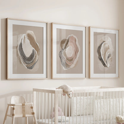 Neutral beige oyster art, three-piece artwork in natural wood matted frames, watches over the nursery bassinet with warm, organic coastal calm.