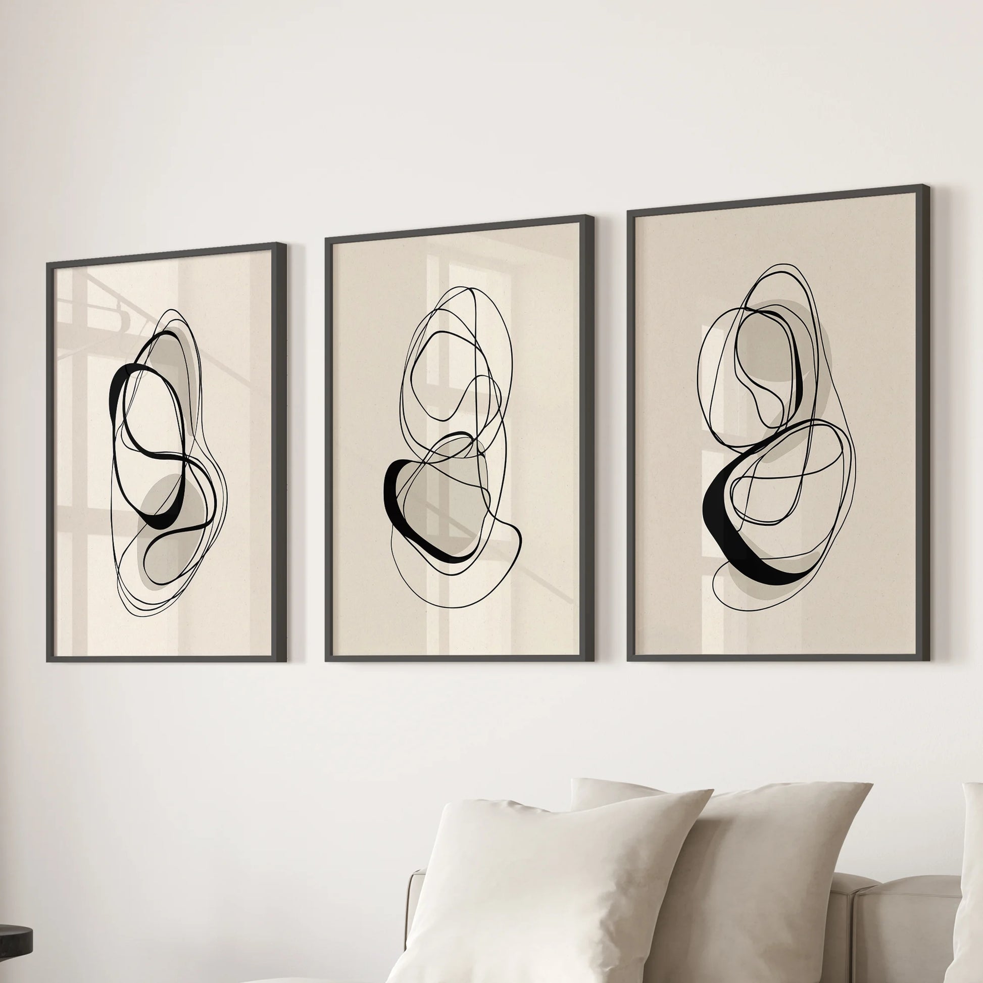 Scandinavian neutral prints in a set of three wall art prints, black frames grounding the family room above the sectional for an airy, minimalist accent.