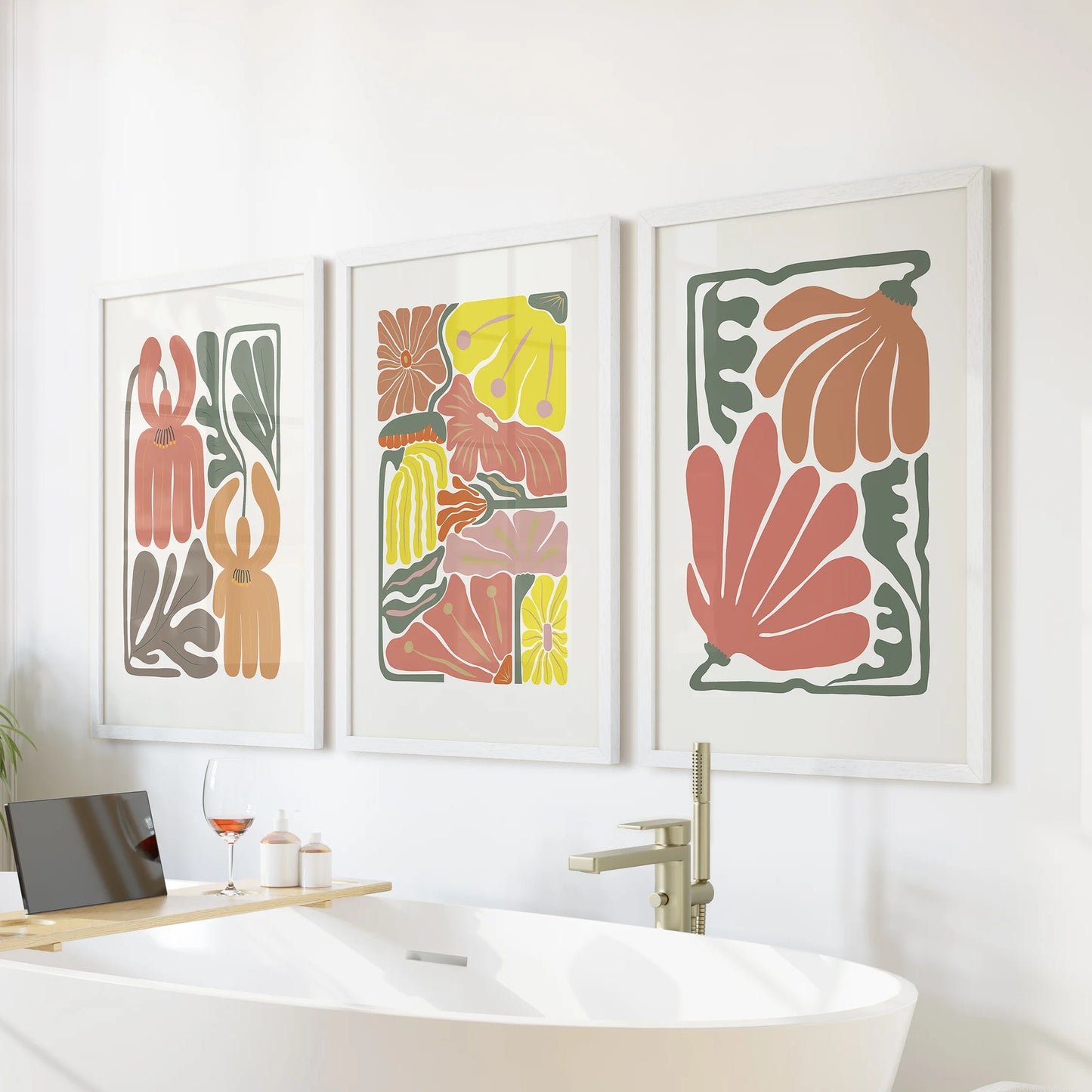 Three vintage-tone floral prints in white frames hang above the tub, blending soft terracotta and airy botanicals for a calm bathroom accent.