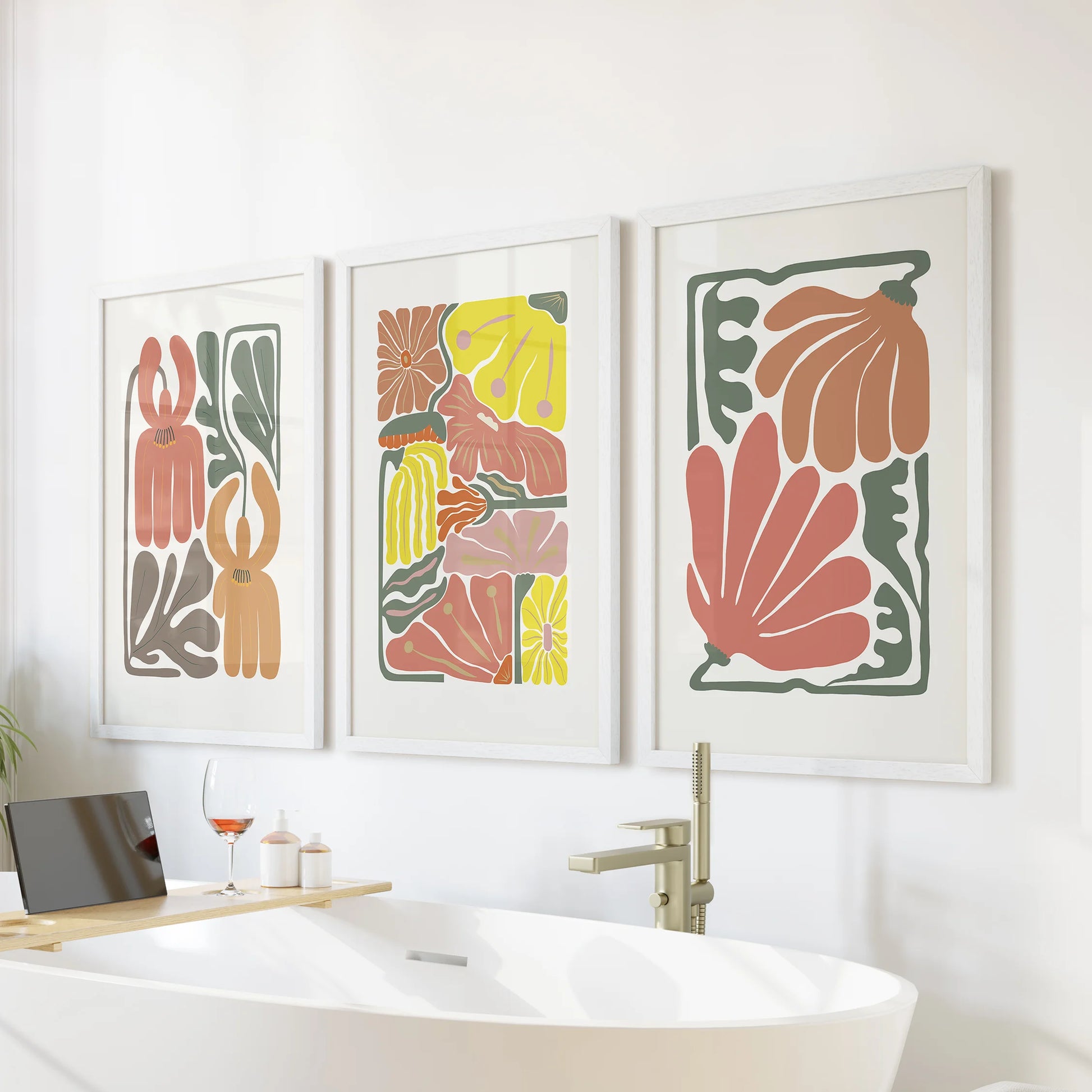 Three vintage-tone floral prints in white frames hang above the tub, blending soft terracotta and airy botanicals for a calm bathroom accent.