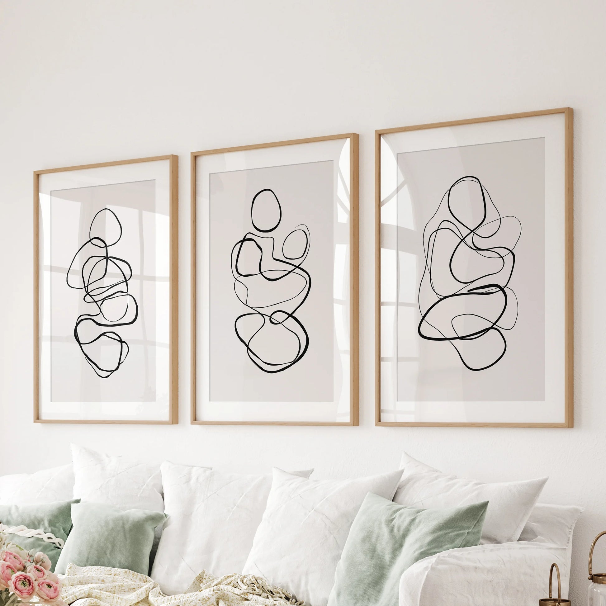 Abstract line art in a wall art trio features wooden frames with mats for the family room, arranged cleanly behind the couch.
