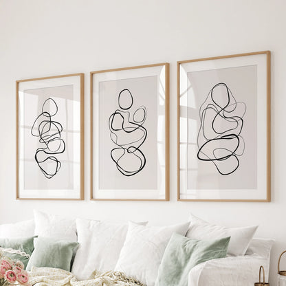 Abstract line art in a wall art trio features wooden frames with mats for the family room, arranged cleanly behind the couch.