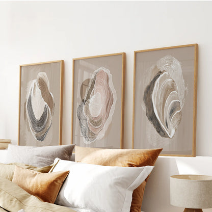 A three-panel oyster wall hanging in natural wood frames crowns the headboard, offering relaxed bedroom elegance with coastal ease.