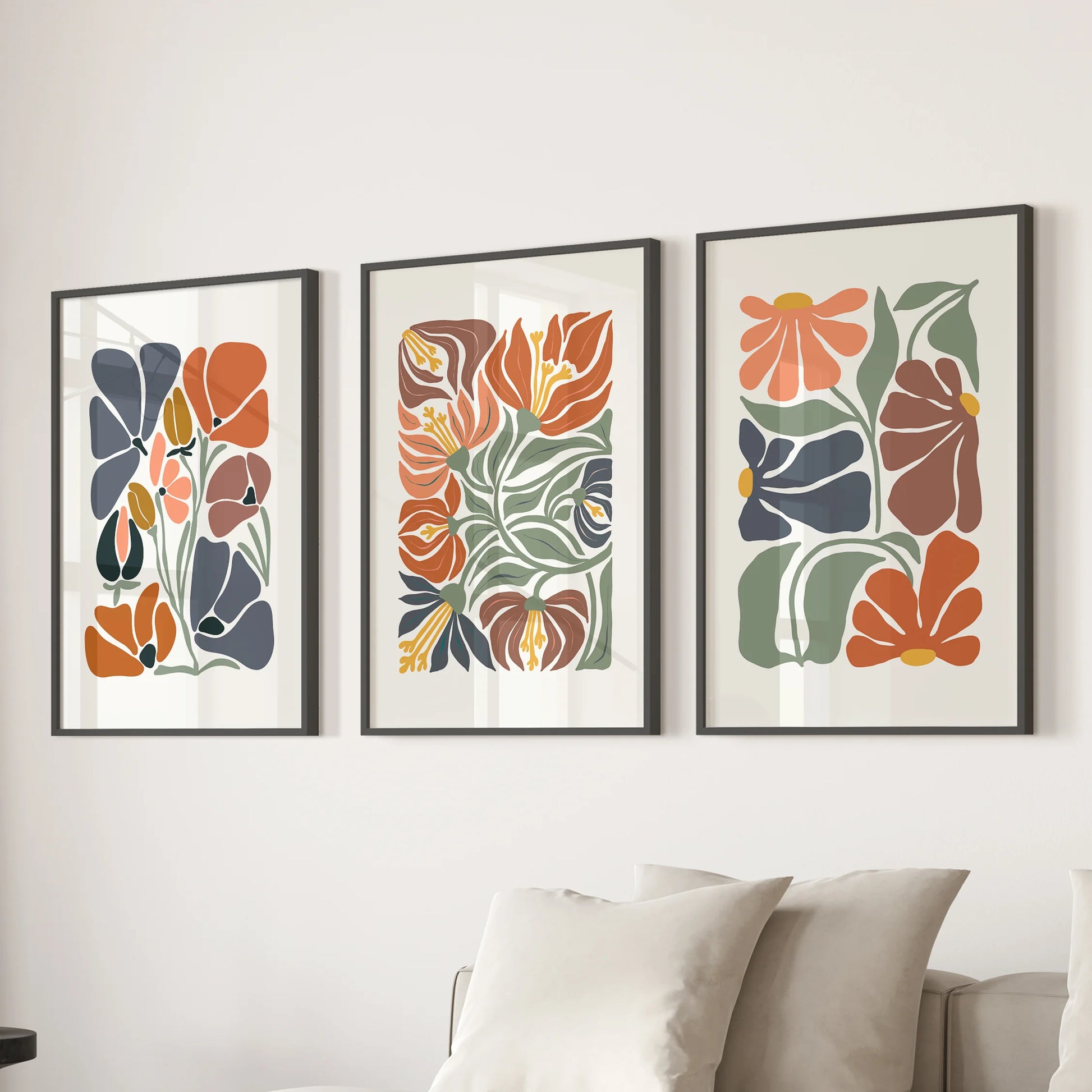 A trio of black-framed abstract floral prints creates a soft focal wall above the family-room sofa with fresh, modern greenery.