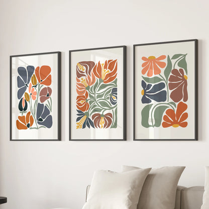 A trio of black-framed abstract floral prints creates a soft focal wall above the family-room sofa with fresh, modern greenery.