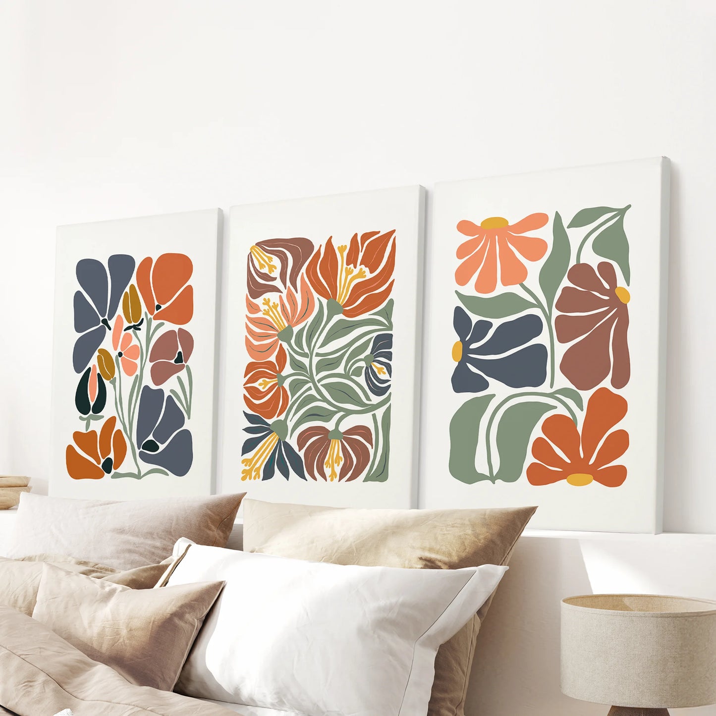 Boho floral canvases, a set of three frameless pieces, float above the bedroom headboard with soft terracotta botanicals and a calm, airy feel.