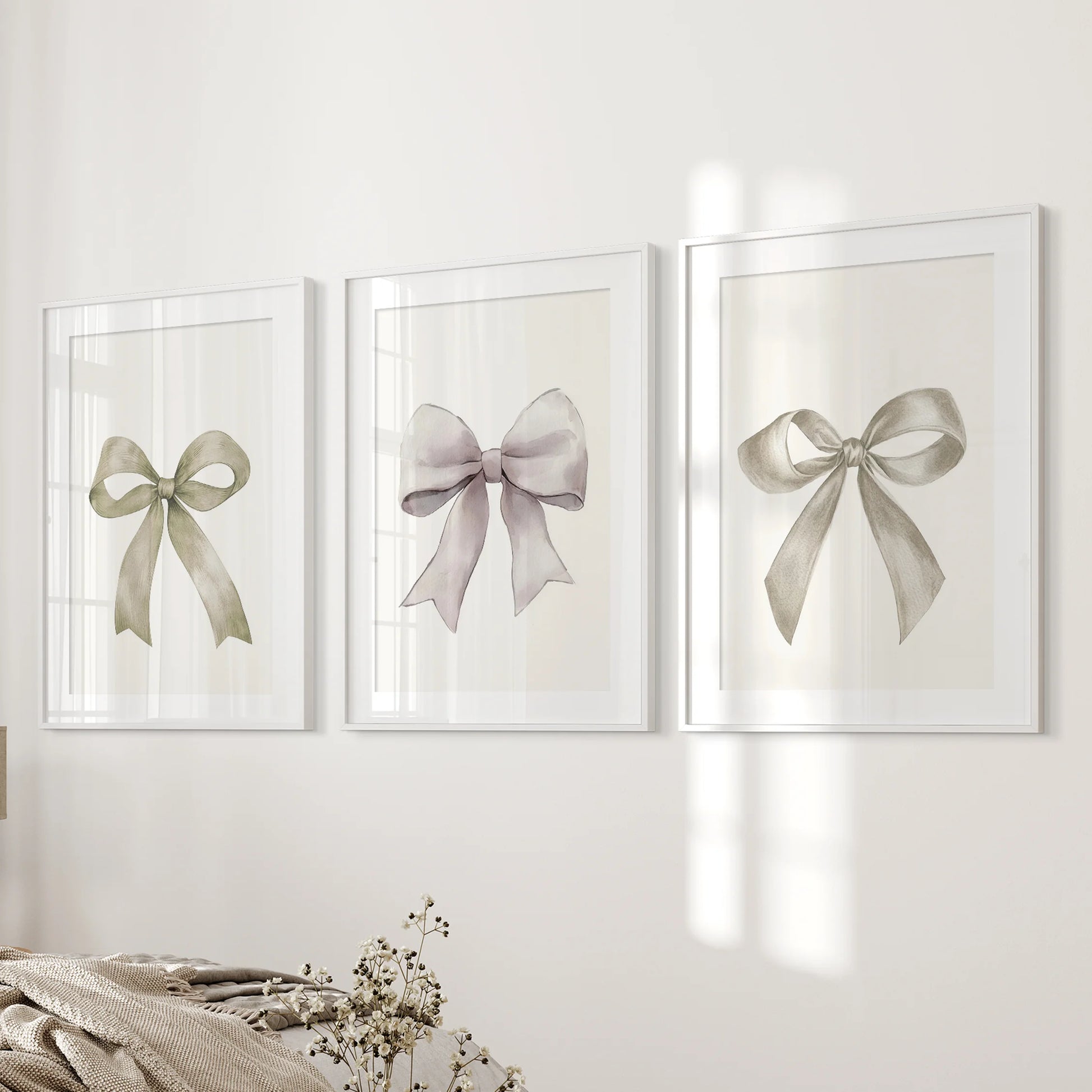 Cream ribbon posters, three white-matted framed prints, style the bedroom wall beside the bed with clean lines and a softly romantic bow theme.